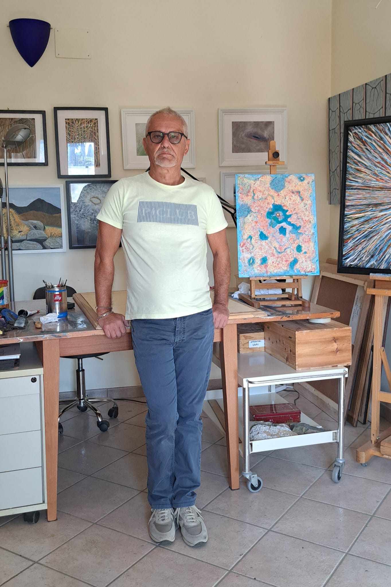 Giancarlo Carnevale in his studio, surrounded by paintings and easels.